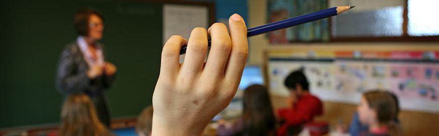 Une main levée qui tient un crayon en classe. PROF/FWB/Michel Vanden Eeckhoudt