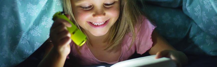 Jeune fille qui lit un livre dans le noir  Fotolia / Wordley Calvo Stock